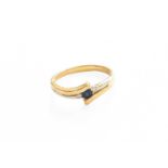 An 18 Carat Two Colour Gold Sapphire and Diamond Crossover Ring, the round cut sapphire flanked by