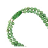 A Jade Two Row Necklacethe 46:51 graduated jade beads knotted to clasp formed of a carved and