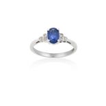 A Sapphire and Diamond Ringthe oval cut sapphire in a white four claw setting, to stepped eight-