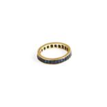 A Synthetic Sapphire Eternity Ring, the calibré cut synthetic sapphires in a yellow channel setting,