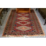 A Kashmir Bukhara Rug, the deep brick red field with column of stepped medallions enclosed by