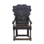 A 17th Century Joined Oak Wainscot Armchair, the scrolled and vine carved top rail above a fielded