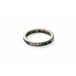 An Emerald and Diamond Eternity Ring, trios of round brilliant cut diamonds spaced by square cut