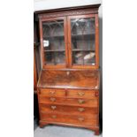A George III Mahogany Bureau Bookcase, with blind fret carved frieze, glazed bookcase top and on