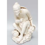 A Chinese Blanc de Chine Porcelain Figure of a Fisherman, seated on a rocky outcrop, impressed