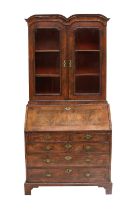 A George II Walnut, Crossbanded and Featherbanded Bureau Bookcase, circa 1730, the moulded cornice