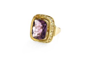 An Amethyst Ring, the rectangular cushion shaped amethyst in a yellow rubbed over setting, to a