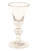 A Baluster Wine Glass, circa 1710, the bell-shaped bowl with basal air tear on an everted baluster