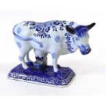 A Dutch Delft Model of a Cow and Milkmaid, 19th century, modelled stood over a pail with the maid
