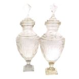 A Pair of Cut Glass Urns and Covers, 19th century, the domed covers with faceted finials over