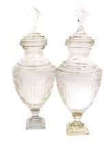 A Pair of Cut Glass Urns and Covers, 19th century, the domed covers with faceted finials over