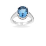 A Blue Topaz and Diamond Ring the oval cut blue topaz in a white four claw setting, to eight-cut