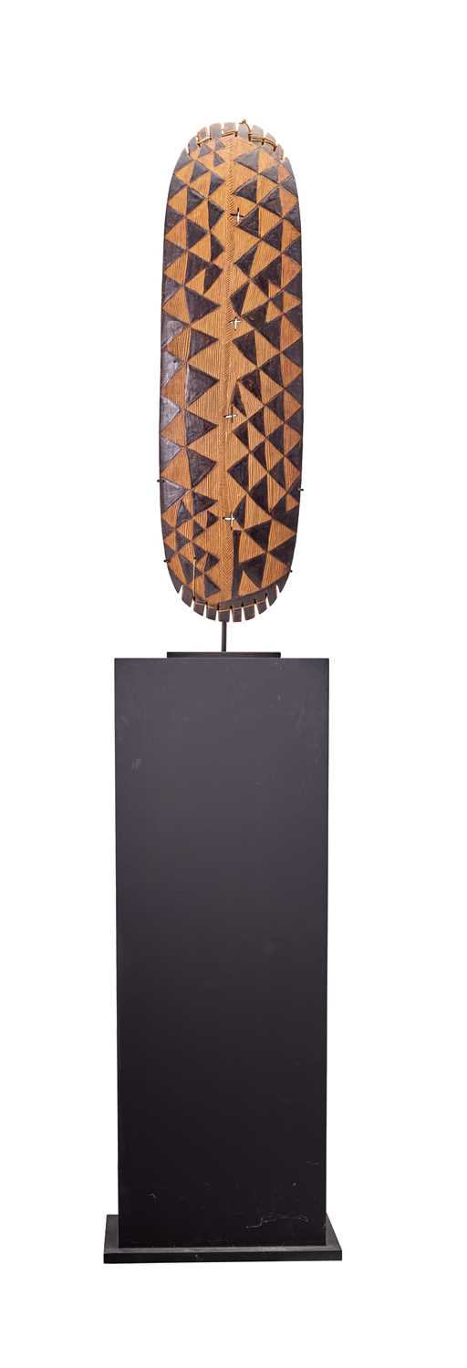 An East African Light Wood Harp, of slighly convex oblong form, carved and stained in black with