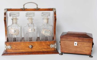 An Oak Three Bottle Tantalus, with three silver decanter labels for Brandy, Rum and Sherry (with