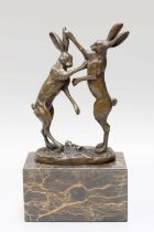 A Contemporary Bronze Sculpture of Boxing Hares, signed Nick, on a marble base, 25cm high