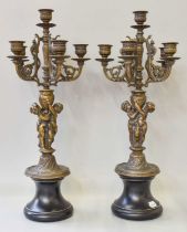 A Pair of Patinated Figural Six Light Candelabra, the pedestals formed as a pair of embracing putti,