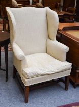 A George III Wing Back Armchair, in later cream coloured upholstery Usual wear to the legs