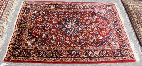 A Kashan Rug, the cherry field of vines centered by an indigo medallion, enclosed by meandering vine
