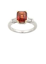 An 18 Carat White Gold Orange Sapphire and Diamond Ring the emerald-cut orange sapphire in a claw
