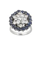 A Sapphire and Diamond Cluster Ring the raised central round brilliant cut diamond within a double