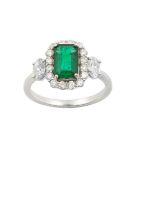 An Emerald and Diamond Cluster Ring the emerald-cut emerald within a border of round brilliant cut