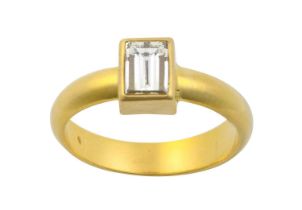 A Diamond Solitaire Ring the fancy rectangular step-cut diamond in a yellow rubbed over setting,