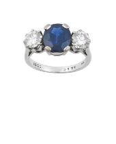 A Sapphire and Diamond Three Stone Ring the oval cut sapphire flanked by round brilliant cut