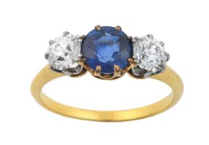 A Sapphire and Diamond Three Stone Ring the round cut sapphire in a yellow claw setting, flanked