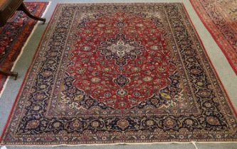 Kashan Carpet, the raspberry field of palmettes and vines centered by an indigo and ivory medallion,