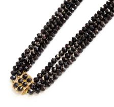 A Garnet Three Strand Necklace, three strands of faceted garnet beads knotted to a rectangular clasp