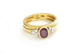 An 18 Carat Gold Ruby and Diamond Ring, the oval cut ruby in a yellow rubbed over setting, flanked