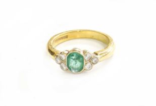 An 18 Carat Gold Emerald and Diamond Ring, the oval cut emerald flanked by trios of round