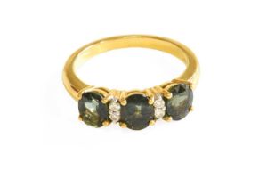 A Green Sapphire and Diamond Ring, three oval green sapphires in yellow claw settings, spaced by