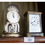 Brass carriage clock and a Shatz 8 day clock under a dome