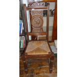 Pair of carved oak dining chairs, with portrait roundel to back and rush seat