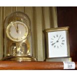 Brass carriage clock and a Shatz 8 day clock under a dome