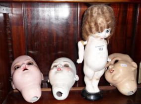 A plaster Kewpie doll and three other dolls heads