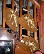 Three spelter cherub wall lights mounted on wood