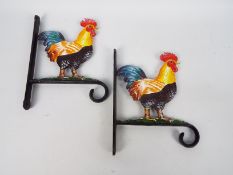 Two cast iron flower basket hangers with cockerel decoration,
