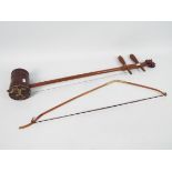 A Chinese erhu, with dragon carved head, snake skin covered resonator and bamboo bow,