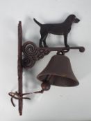 A cast iron, wall mountable, bell with canine surmount, approximately 36 cm (h),