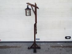 An adjustable, wooden standard lamp with lantern style light,