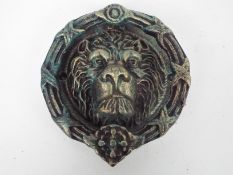 A cast iron door knocker in the form of a lion's head, approximately 21 cm (d),