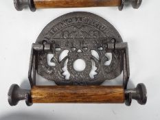 A pair of cast iron and wood toilet roll holders marked St Pancras Fixture,