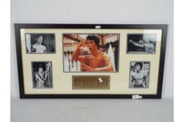 A framed Bruce Lee photograph montage with informational plaque, approximately 40 cm x 75 cm.