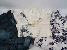 A collection of traditional Japanese clothing to include a silk kimono decorated with chrysanthemum.