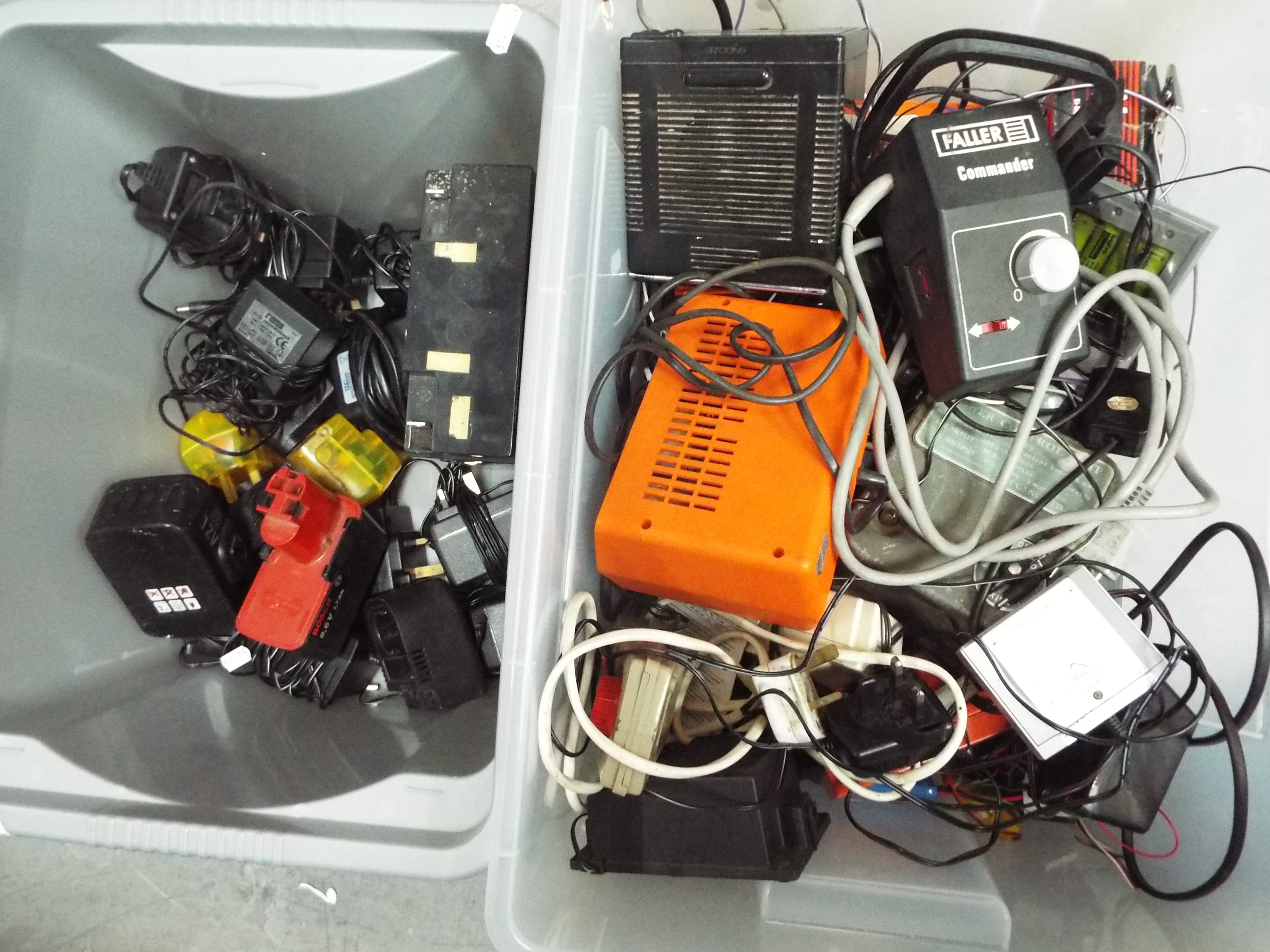 Two boxes containing various chargers, batteries, controllers and similar.