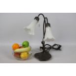 An Art Nouveau style, twin branch, table lamp, 42 cm (h) and a glass bowl containing faux fruit.