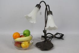 An Art Nouveau style, twin branch, table lamp, 42 cm (h) and a glass bowl containing faux fruit.