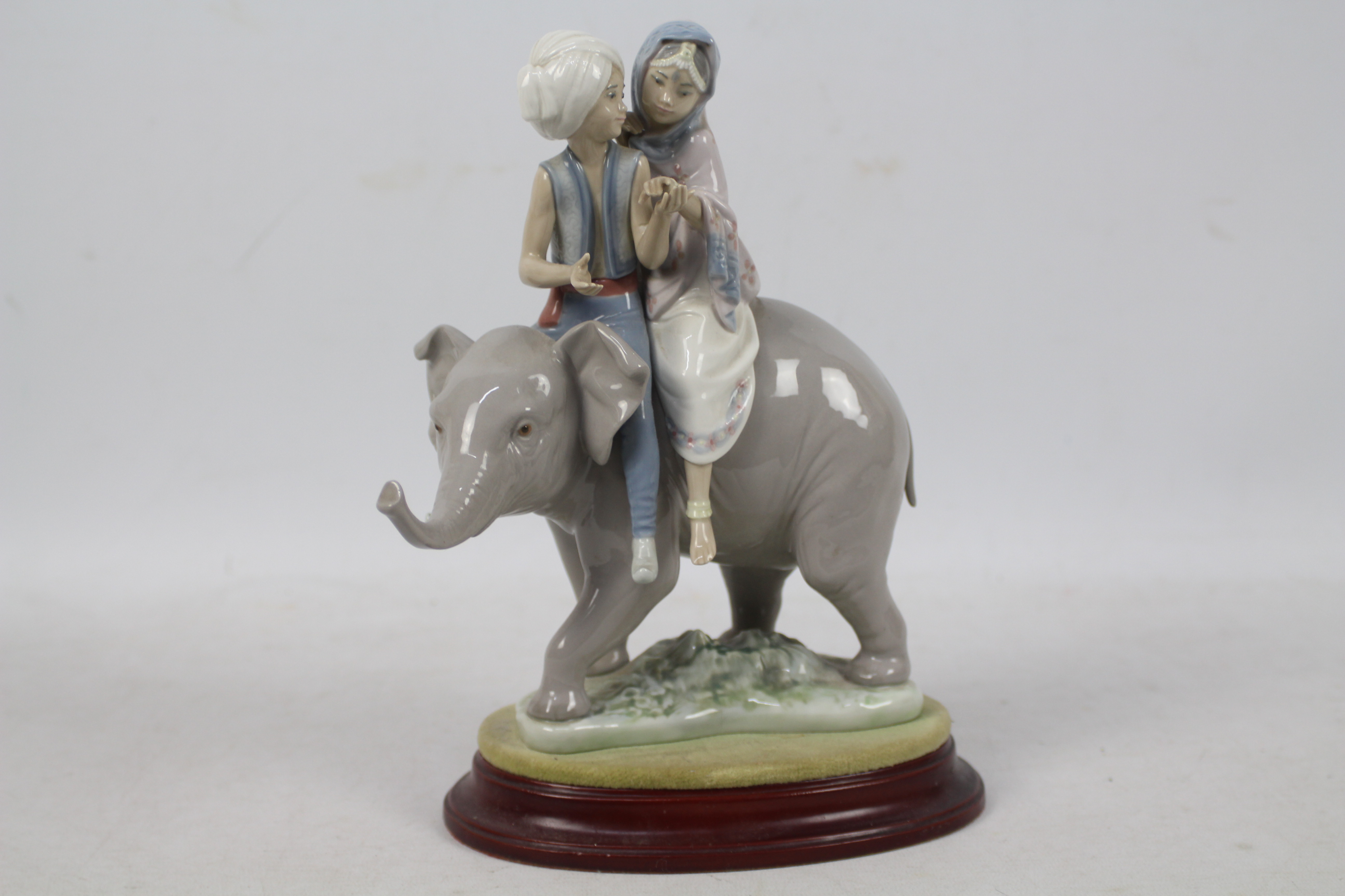 A Lladro figure group # 5352 Hindu Children, approximately 23 cm (h), with wooden display base.